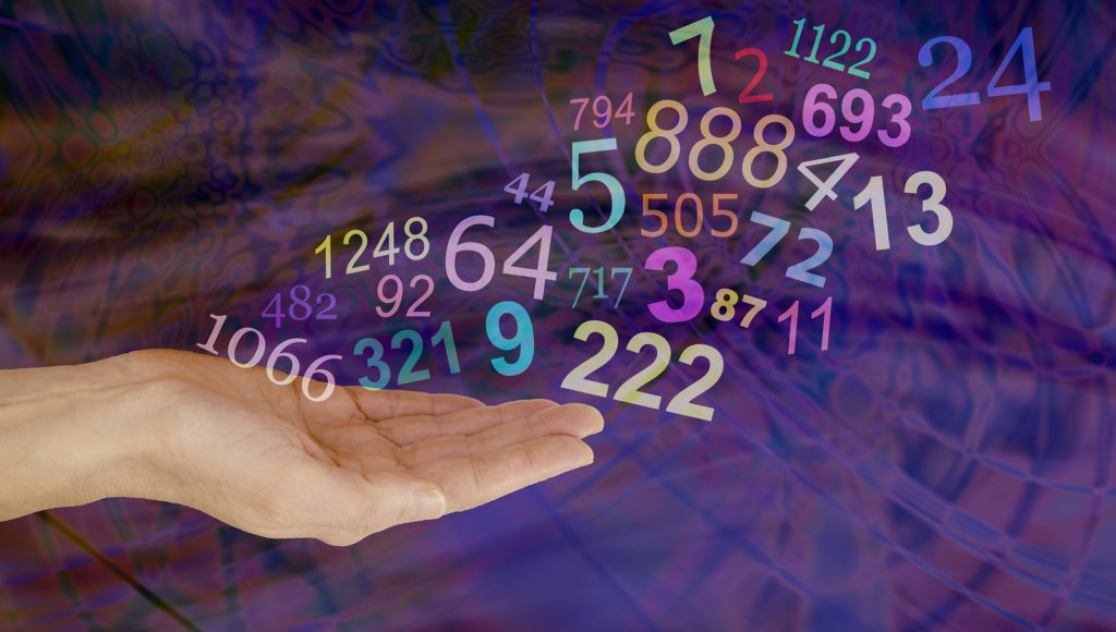 What do your Numbers mean - female hand palm up with a group   of random multicolored transparent numbers floating up and away on a dark multicolored background with copy space